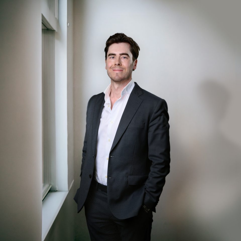Erik Malmberg, partner at Monfido a Newground company, standing in a minimalistic office setting by a window.